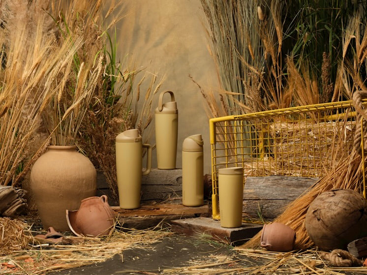 Autumn Vista bottles arranged in an autumn backdrop with wheat, pottery, and a yellow cart
